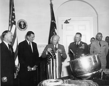 August 15, 1960 - Dwight D. Eisenhower holds the American flag which was carried in the Corona capsule retrieved from Discoverer XIII.